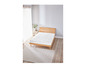 Un matelas blanc sur un cadre de lit en bois dans une chambre à coucher claire.