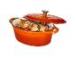 Une cocotte orange contenant de la viande et des légumes.