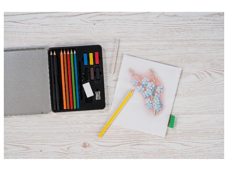 Kit d'art avec crayons de couleur, pastels et croquis floral sur une table en bois.