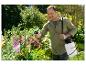 Homme souriant utilisant un pulvérisateur de jardin Parkside sur des fleurs.