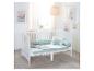 Lit bébé blanc avec literie vert menthe et coussins décoratifs dans une chambre lumineuse.