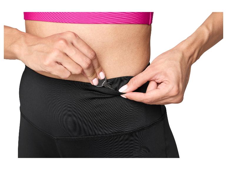 Femme mettant une clé dans la poche d'un legging de sport noir.