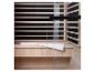 Sauna infrarouge avec intérieur en bois, porte vitrée et une serviette blanche sur le banc.