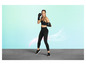 Une femme en tenue de sport et en gants de boxe pose dans un studio.