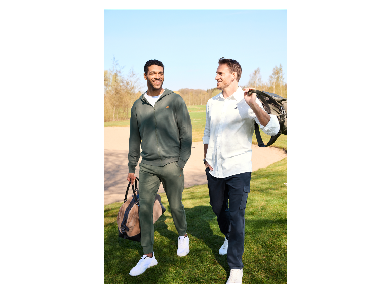Deux hommes marchent sur un terrain de golf avec des sacs de voyage.