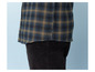 Une chemise à carreaux bleu et marron avec un pantalon en velours côtelé noir.