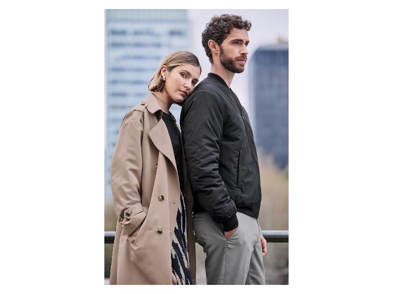 Un couple élégamment vêtu pose sur un fond urbain.