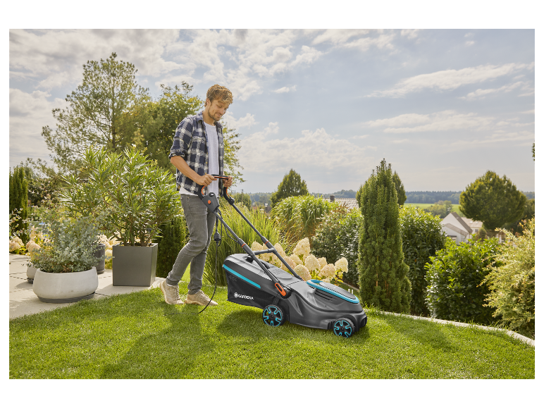 Un homme utilise une tondeuse à gazon électrique Gardena dans son jardin.