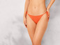 Une femme porte un bas de bikini orange.