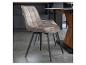 Chaise de salle à manger rembourrée beige avec pieds en métal noir à côté d'une table en bois.
