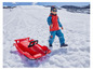 Un enfant tire un traîneau rouge en forme de voiture de course dans la neige.