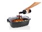 Une main verse du vin dans un plat à rôtir contenant un poulet et des légumes.