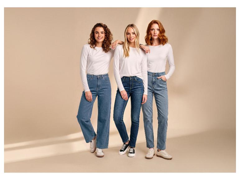 Trois femmes portent des t-shirts blancs à manches longues et des jeans, posant sur un fond beige.