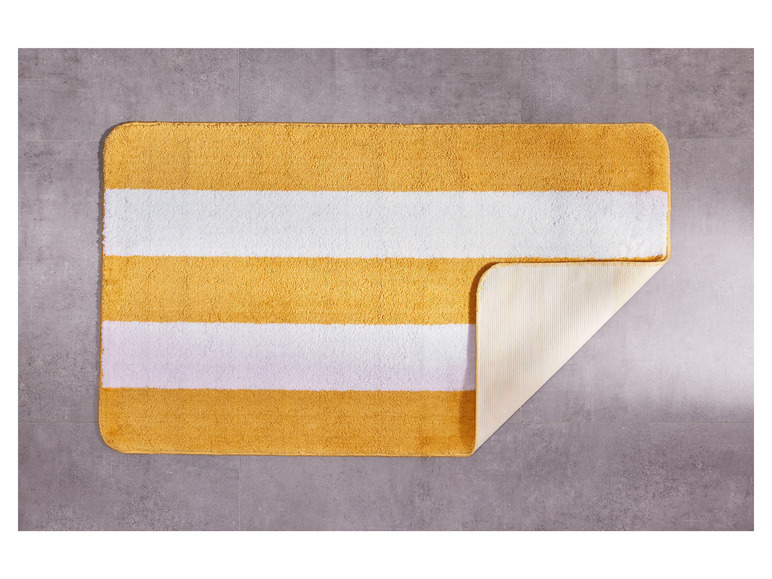 Un tapis de bain jaune et blanc rayé avec un dos antidérapant.