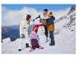 Une famille vêtue d'habits d'hiver construit un bonhomme de neige dans les montagnes.