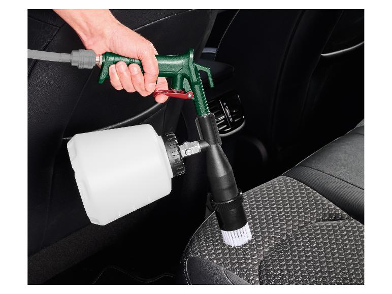 Main tenant un pistolet de nettoyage de voiture avec brosse, nettoyant un siège de voiture.