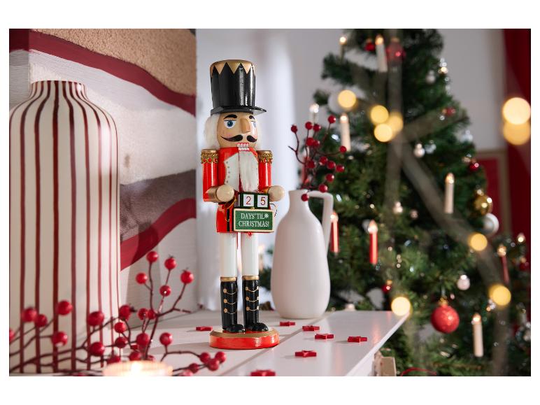 Figurine de casse-noisette avec un panneau de compte à rebours de Noël sur une cheminée.