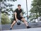 Un homme en tenue noire jouant au basket-ball en plein air.