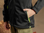 Une veste noire avec des détails verts et une poche zippée.