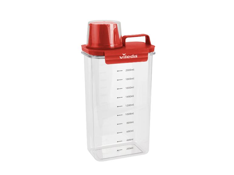 Récipient doseur transparent avec couvercle et poignée rouges, gradué jusqu'à 2000 ml.