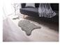 Un tapis en fausse fourrure gris en forme de peau de mouton dans un salon avec un canapé.