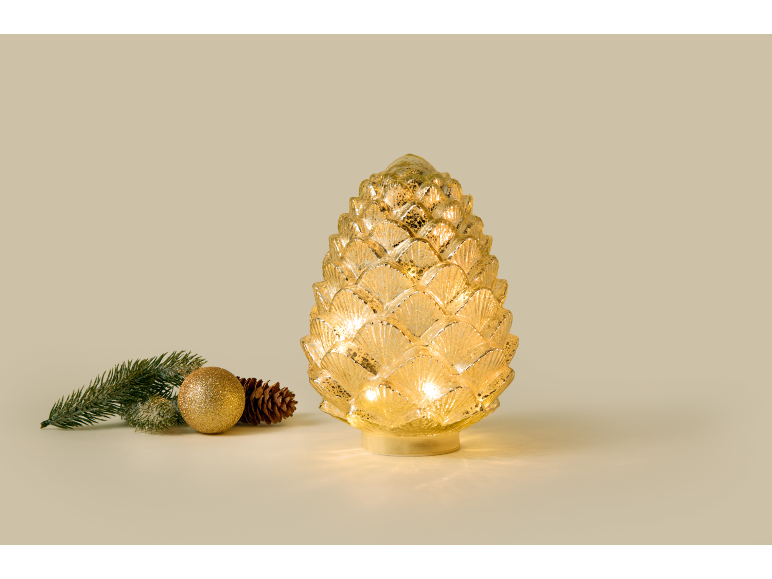Pomme de pin décorative lumineuse en verre avec des décorations de Noël à côté.