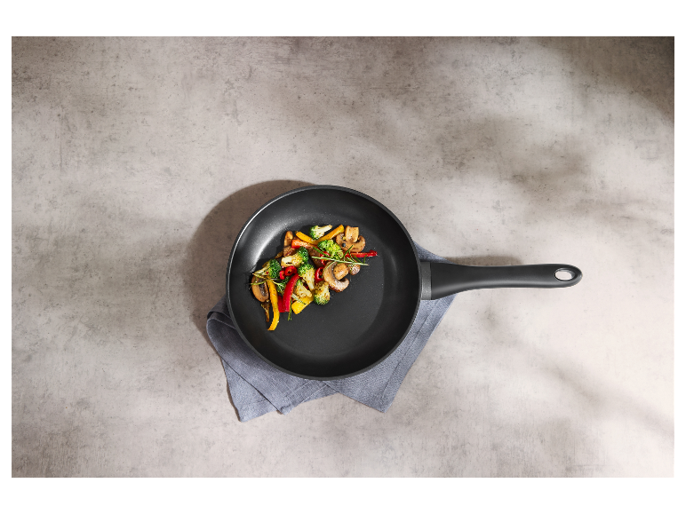 Une poêle noire avec des légumes sautés.