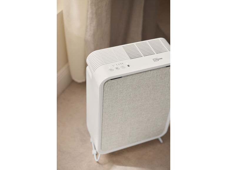 Purificateur d'air blanc avec panneau frontal en tissu gris clair et boutons de commande.