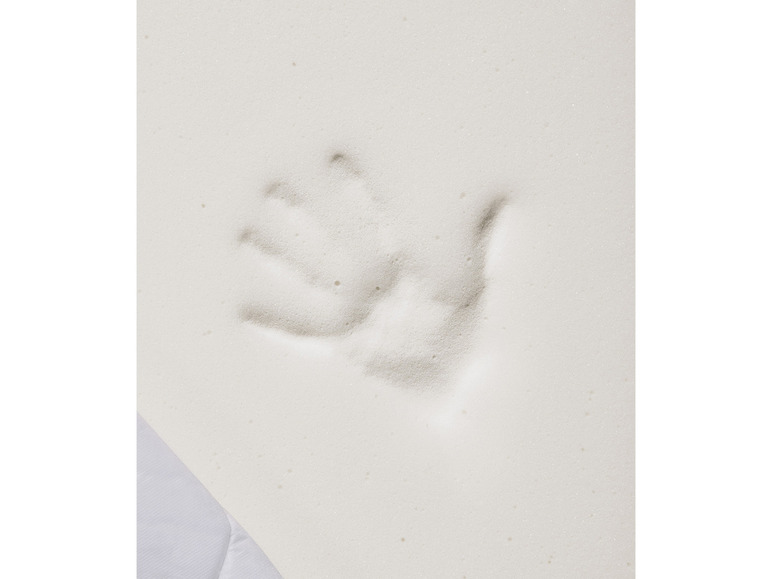 Une empreinte de main sur un matelas en mousse blanche.