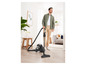 Un homme utilise un aspirateur dans une maison moderne.
