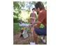 Père et fils font un barbecue portable, une fille assise sur une couverture en arrière-plan.