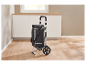 Un chariot de courses pliable noir avec fonction de refroidissement se trouve sur un sol en bois.