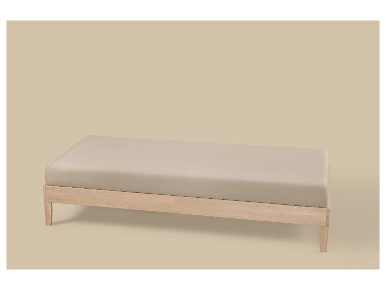 Banc rembourré beige clair avec cadre en bois clair sur fond beige.