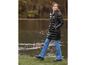Une femme porte une doudoune noire et un jean bleu, marchant le long d'un lac.