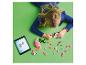Une fille construit un flamant rose avec des briques de construction, suivant les instructions sur une tablette.