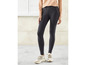 Une femme porte un jean skinny noir et des baskets blanches.