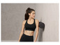 Une femme en brassière de sport et leggings noirs utilise un rouleau en mousse.