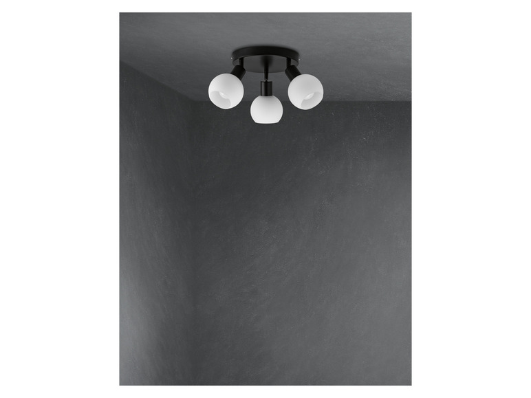 Plafonnier noir avec trois abat-jours en verre ronds.