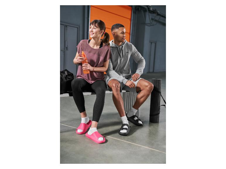 Femme et homme en tenue de sport et claquettes assis sur un banc après l'entraînement.