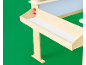 Détail d'un chevalet en bois clair avec plateau et tableau blanc sur fond vert.