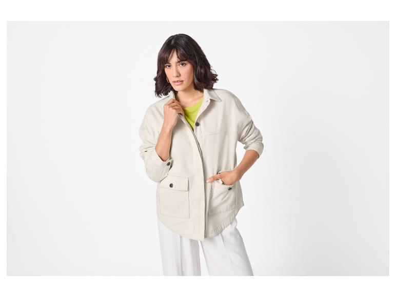 Femme en veste utilitaire beige clair, haut vert citron et pantalon blanc à jambes larges.