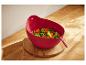 Salade rouge en plastique avec des légumes cuits sur une surface en bois.