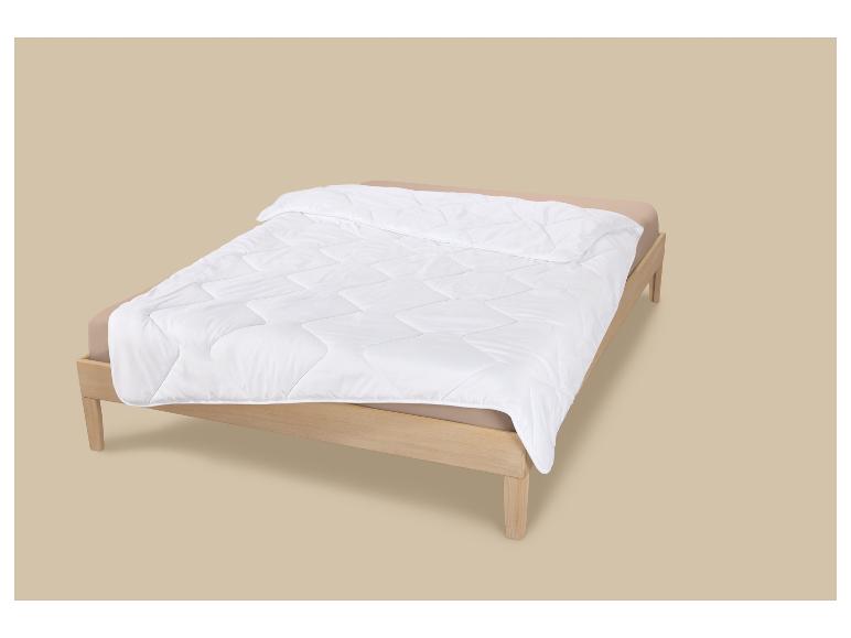 Lit en bois avec linge de lit beige et couette blanche matelassée.