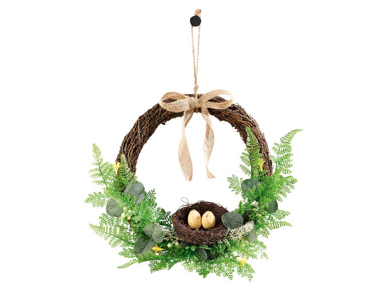 Couronne de Pâques avec un nid et deux œufs, ornée de feuillage vert et d'un nœud en jute.