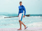 Homme avec équipement de paddleboard, y compris un t-shirt Mi, un short et une pagaie