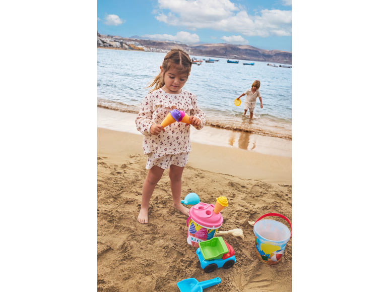 Enfants jouant sur la plage avec des jouets de sable, seaux et pelles.