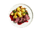 Rôti de bœuf avec pommes de terre, champignons et sauce aux baies sur une assiette blanche.