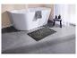 Tapis de bain gris moderne devant une baignoire blanche.