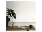 Bureau en bois avec livre ouvert, tasse, vase avec plante et motif grec sur le mur.