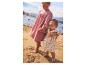 Deux filles en robes d'été sur la plage, l'aînée tenant la main de la plus jeune.